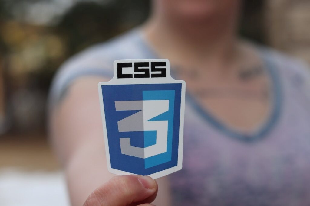 Uma pessoa com rosto embaçado segura o logo da linguagem de marcação CSS3.