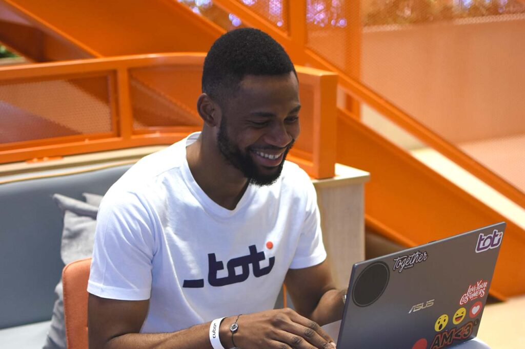 Jovem negro, aluno da Toti, sentado em frente a um notebook aprendendo a programar.